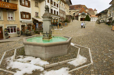 GRUYERES, SWITZERLAND - DECEMBER 11, 2009: Unidentified people walk by the square of the medieval town of Gruyeres, Switzerland.のeditorial素材