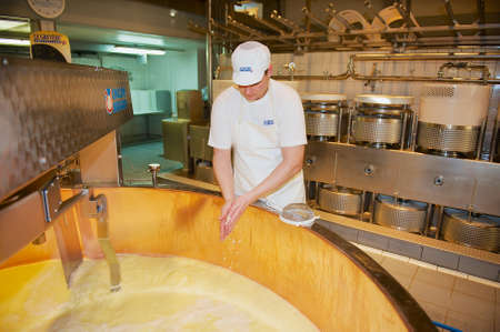 Gruyeres, Switzerland - December 11, 2009: Unidentified worker makes cheese at a cheese factory in Gruyeres, Switzerland.のeditorial素材
