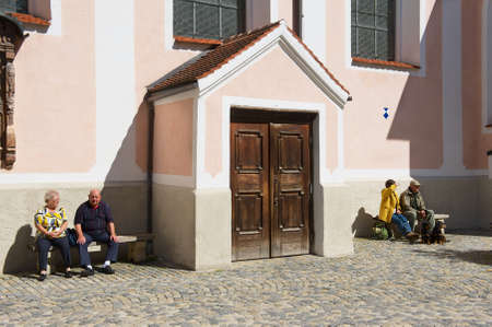 Mittenwald, Germany - September 01, 2010: Unidentified, senior tourists relax at the street next to the cathedral of Mittenwald, Germany.のeditorial素材