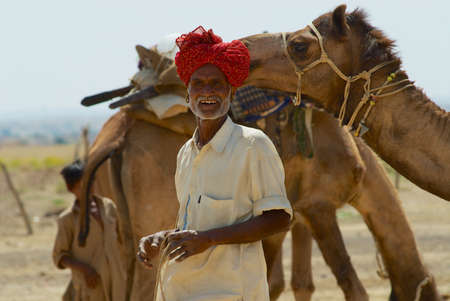 Jodhpur, India - April 04, 2007: Unidentified man wearing turban and traditional dress gets his camel ready for a safari ride in the desert near Jodhpur, India.のeditorial素材