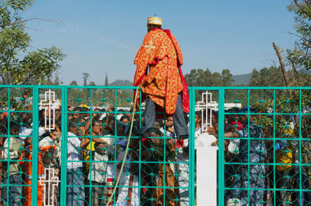 Addis Ababa, Ethiopia - January 19, 2010: Young Orthodox priest splashes water standing on the fence...