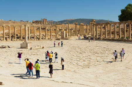Jerash, Jordan - August 19, 2012: Tourists visit ruins of the Forum (Oval Plaza) and Colonnade street in Jerash, Jordan.のeditorial素材