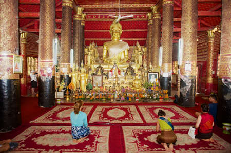 Luang Prabang, Laos - April 16, 2012: People pray in Wat Mai Suwannaphumaham Buddhist temple in Luang Prabang Laos.のeditorial素材