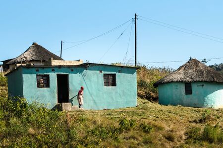African woman out of her traditional mud house in small village, in South Africa. Apartheid,...