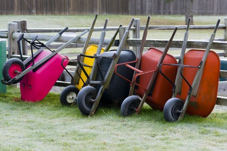 Wheel barrows put away leaning against fence outside of community garden.の写真素材