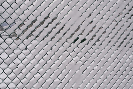 snow filling the holes in a chain link fence.の写真素材