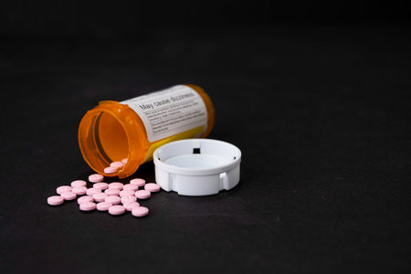A prescription (RX) of medication in the form of pink pills. Some of the pills are outside of the tipped bottle.の写真素材