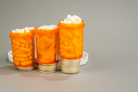 Three overfull prescription bottles stack on a ladder of Silver Dollars. Expense is the concept.の写真素材