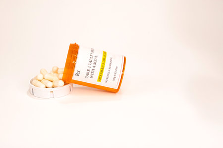A container of prescription APIXABAN spilled on its side. Capsules are spilled into the cap.の写真素材