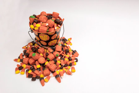 A pile of candy corn overflowing from a bucket. Viewed from an overhead position.