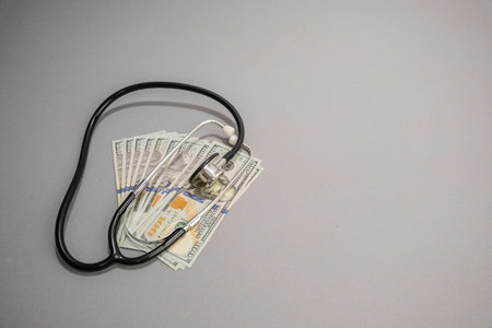 A Stethoscope lying on top of a spread out pile of 100 us dollar bills.の写真素材