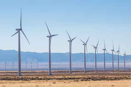 Nine windmills of the first row, and a few of a second row are visible in a large wind farm in Utah.