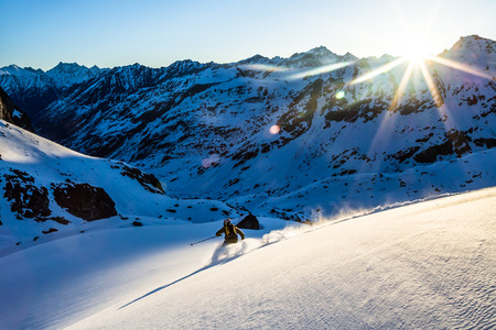 Below the Snowbird hut, a young man skis in the first light of the morning in the backcountry of the...