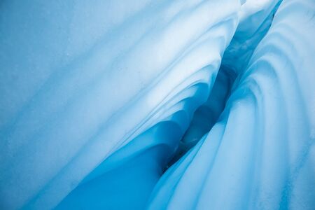 A deep crevasse on the Matanuska Glacier in Alaska. The sides have a wavy texture from water running...