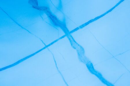 Detail of dark blue cracks through lighter glacier ice. The cracks are refrozen water ice in...