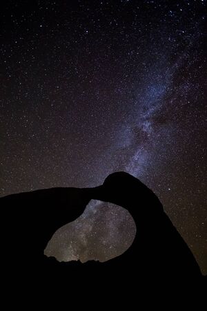 Silhouette of thin arch with night sky above. Starry night with Milky Way Galaxy and universe star clusters.の写真素材