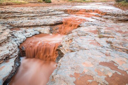 Flooded valley in rising flash flood after a summer rainstorm near Moab, Utah. The water is thick and red with sand and debris from the desert.の写真素材
