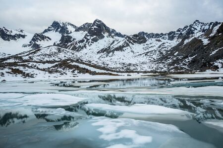 A small alpine lake thawing in spring below Montana Peak in the Alaskan wilderness of the Talkeetna Mountains.の写真素材