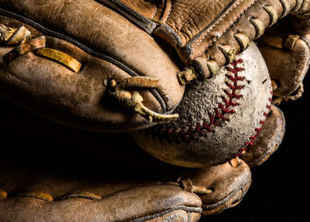 Baseball mitt holding a scuffed up old baseball.の写真素材