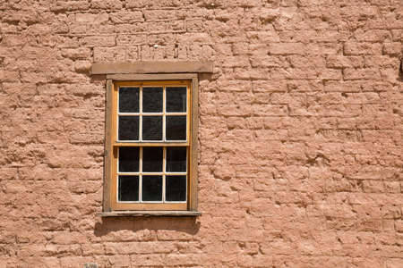 In a small ghost town in the Southern Utah wilderness, a wooden window is set into a red brick...