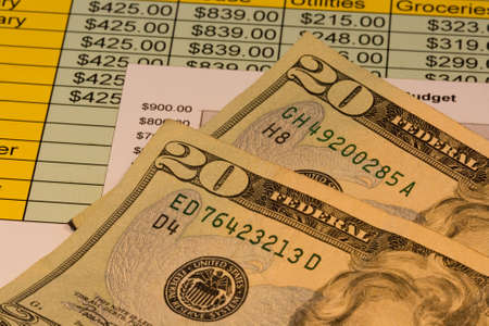 Close up of two american twenty dollar bills along with chart showing budget