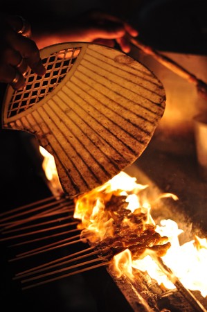 Photo taken in Sabah, Malaysia. Satay on a grill being fanned to fire-up the charcoal.の写真素材