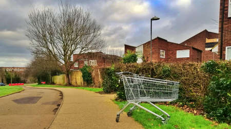 Harlow, England - March 13 2019. A discarded shopping trolley at the side of the pathのeditorial素材