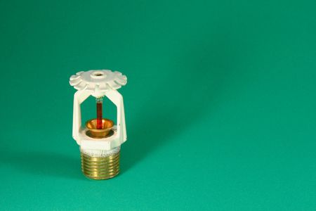 glass filled sprinkler head over a green felt backgroundの写真素材