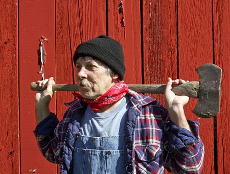 lumberjack portrait in front of a barn with an ax on his shouldersの写真素材