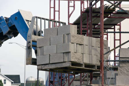 load of bricks being lifted by a fork lift to a scafold