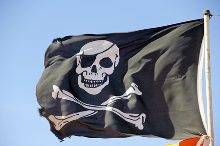pirate flag flying against a blue skyの写真素材