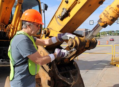 Heavy equipment mechanic working with a wrench on a nut