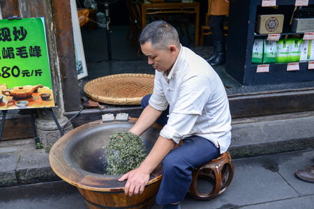 Sichuan, China - November 05, 2014 : Chinese man Stir-drying Tea, Utilized in the process of making tea in the pot to make tea atrophy Microflame wither way, make tea rolled through artificial water evaporate quickly, blocking the tea fermentation processのeditorial素材