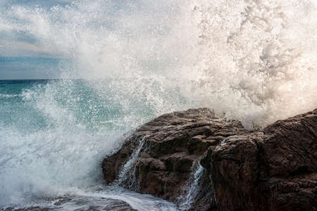 A wave breaking on a coastal rockの写真素材