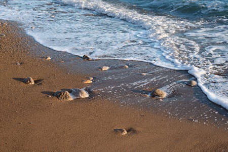 A sandy beach with pebbles and a foamy wave on the Black sea coastの写真素材