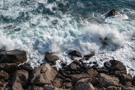 Sea waves breaking on the rocky shore, view from topの写真素材