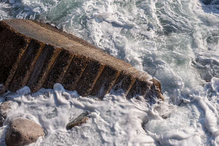 Fragment of the stairs of the destroyed breakwater in the sea surfの写真素材
