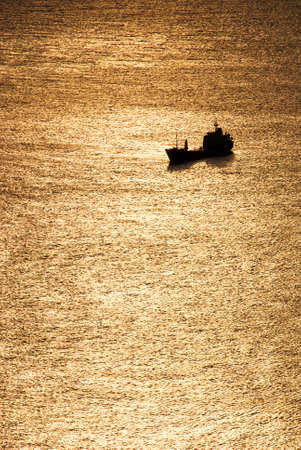 Silhouette of a cargo ship on a sunny seaの写真素材