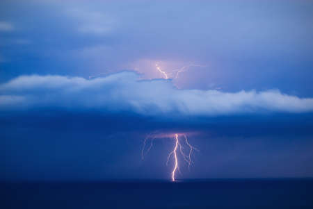 Orange lightning over the sea strikes through the cloud