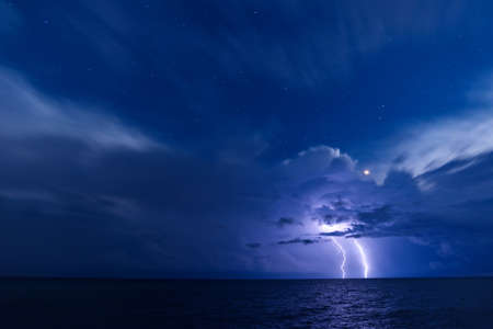 Two lightning bolts over the sea with starry sky backgroundの写真素材
