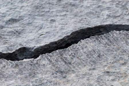 Texture of natural grey limestone with traces of water erosion and diagonal crackの写真素材