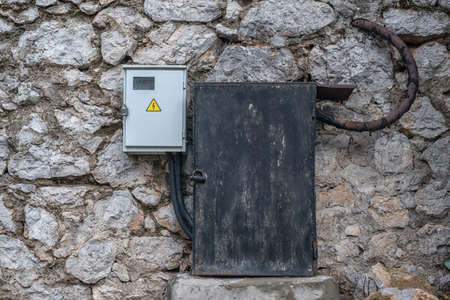 Old and new electrical boxes on a rough stone wallの写真素材