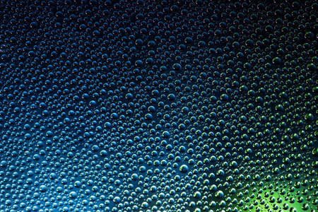 Water drops on the glass with a dark blue green backgroundの写真素材