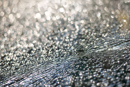 Broken glass texture with selective focus and glittering bokeh backgroundの写真素材