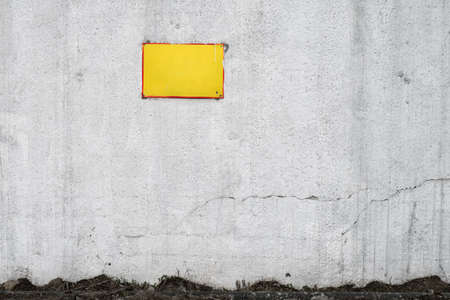 An empty yellow sign on an old cracked concrete wallの写真素材