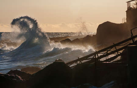 Scenic wave on ruined metal structures and sunset backgroundの写真素材