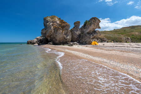 A small yellow tent under a rock on a sandy beachの写真素材