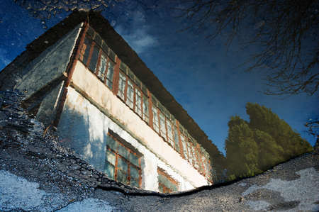 Reflection of an old house in a puddle on the asphaltの写真素材
