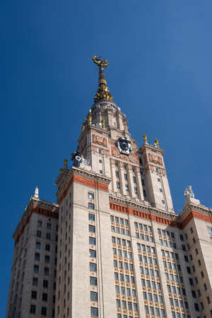 Fragment of a high rise tower in Stalinist monumental architecture style with a gold star and the coat of arms of the USSR on a blue sky backgroundの写真素材