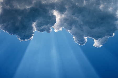 A wide sunbeam on a blue sky under the dark clouds